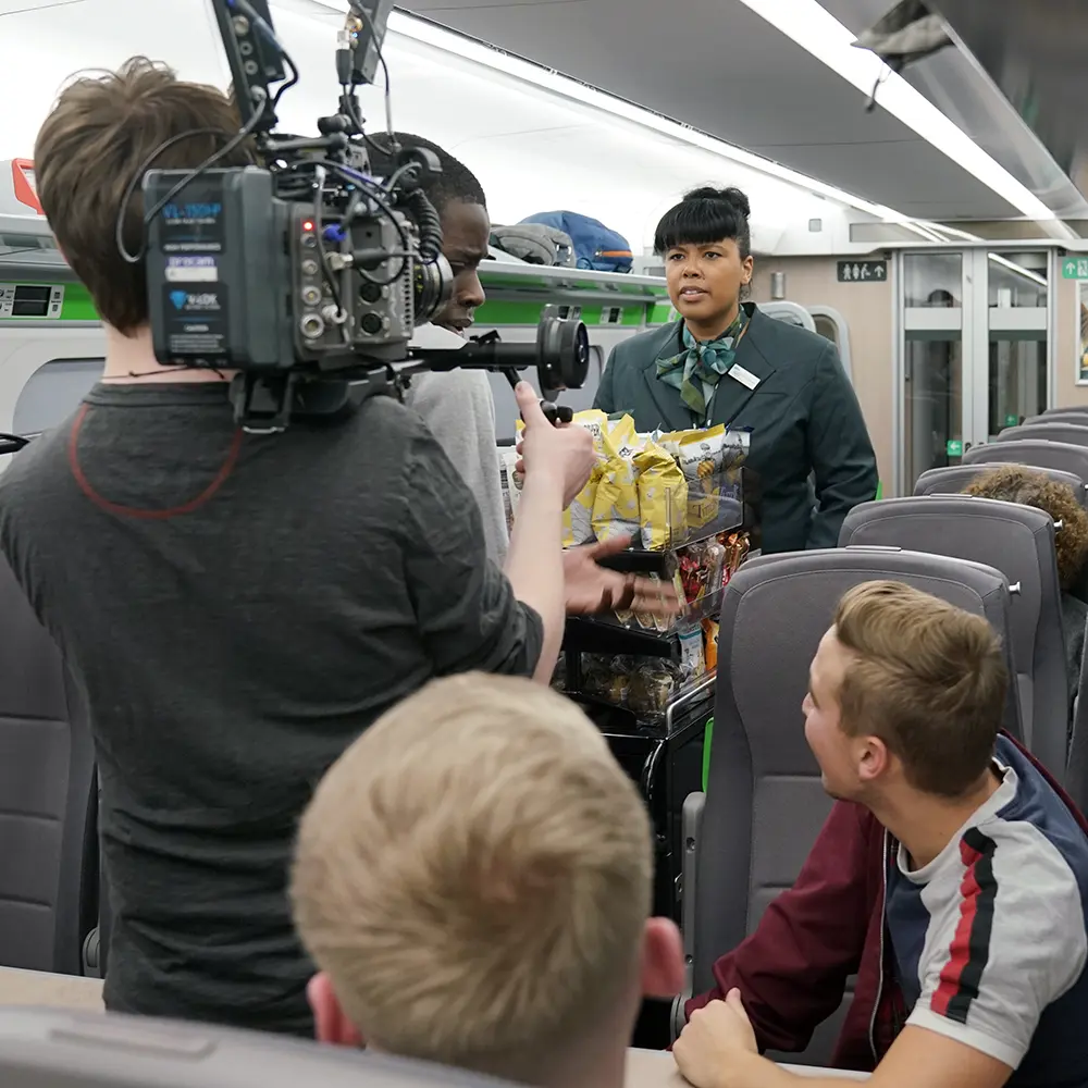 Film crew on board a train filming an employee.